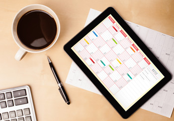 Wall Mural - tablet pc showing calendar on screen with a cup of coffee on a d