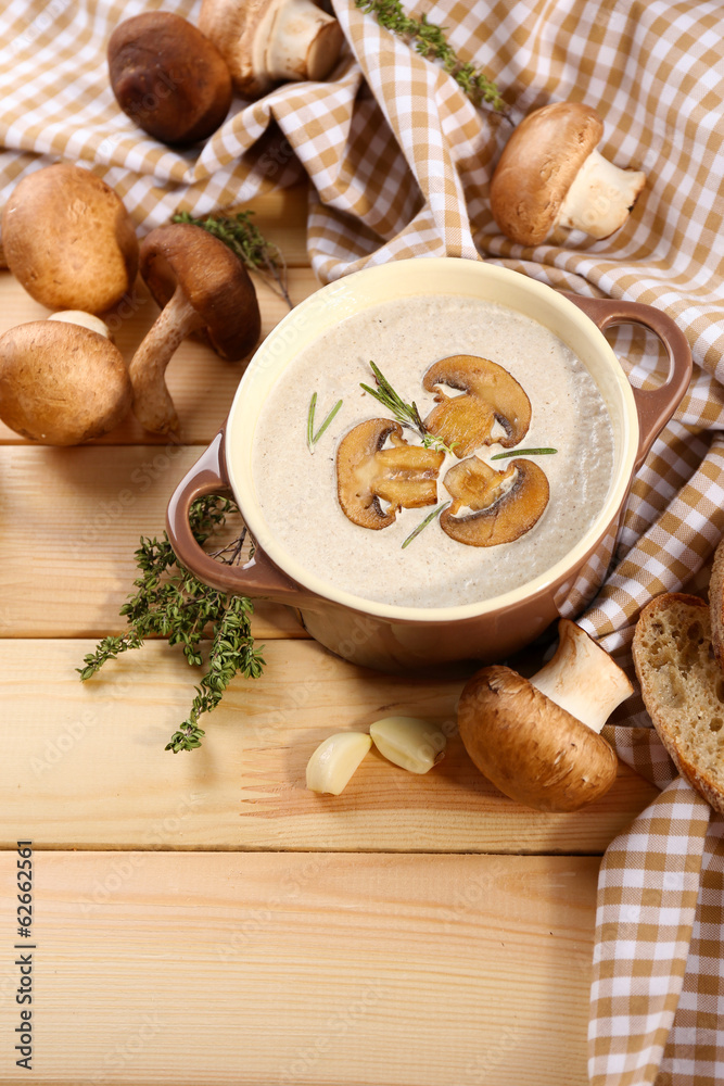 Mushroom soup in pot, on napkin,  on wooden background