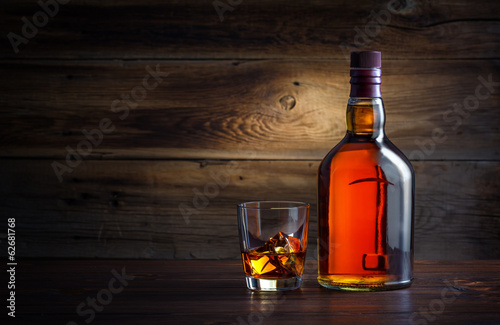 butelka-i-kieliszek-whisky-z-lodem-na-drewnianym-b