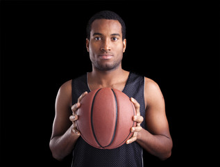 Wall Mural - Portrait of a basketball player holding a ball against dark back