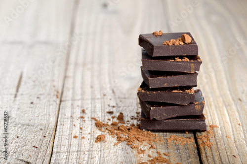 Fotografie, Obraz Pile of chocolate pieces with cocoa on wooden background