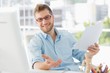 © WavebreakMediaMicro - Happy designer sitting at his desk gesturing at camera
