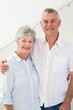 © WavebreakMediaMicro - Happy retired couple standing and smiling at camera