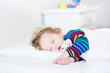 © famveldman - Adorable toddler girl taking a nap in a white bed