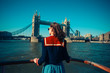 © LoloStock - Young woman on boat looking at Tower Bridge in London