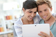 © goodluz - Young couple in sofa websurfing on internet with tablet
