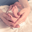 Feet of newborn baby and mother's hands