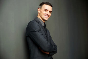 Sticker - Smiling businessman with arms folded standing on gray background