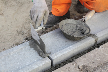 Wall Mural - Worker installing curb stone, using trowel and mortar