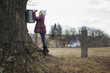 © Mint Images - A maple syrup farm. A young girl holding a bucket which is tapping the sap from the tree.