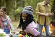 © Mint Images - A campsite clearing in the woods. People seated around a table.