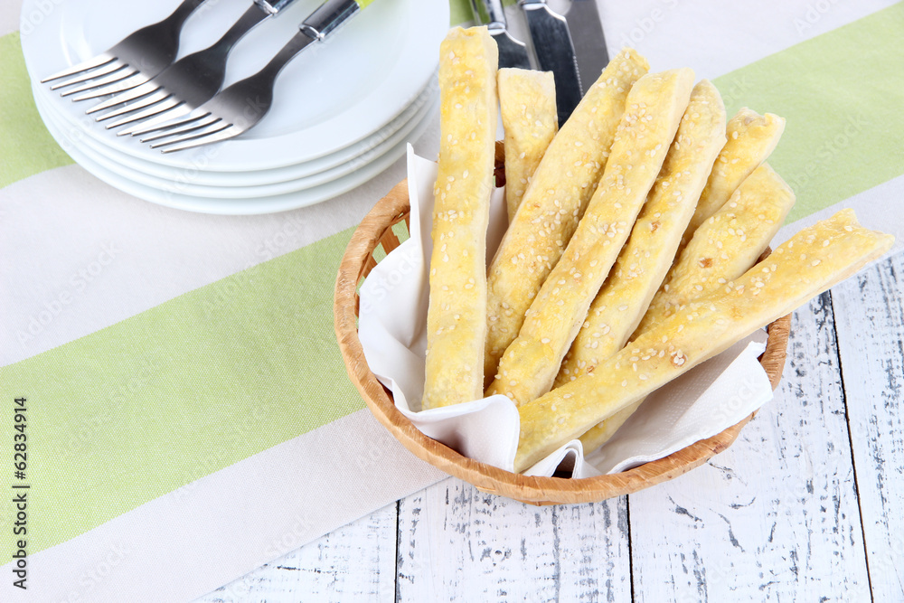 Bread sticks  in wicker basket on wooden background