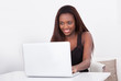 © Andrey Popov - African American woman using laptop at home
