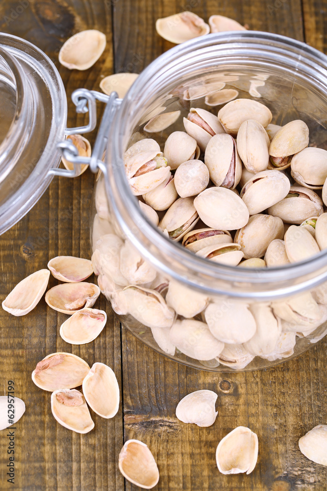 Pistachio nuts in glass jar on wooden background