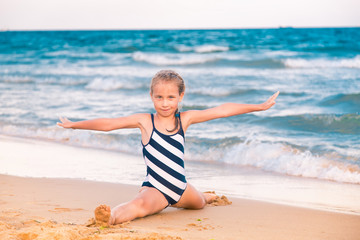 Wall Mural - Beautiful little girl excercising on the beach