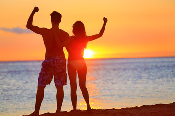 Wall Mural - Sporty fitness couple cheering at beach sunset