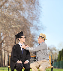 Wall Mural - Graduate student and his proud father sitting in park