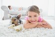Little girl lying on rug with yorkshire terrier smiling at