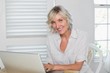© lightwavemedia - Smiling mature woman using laptop at home