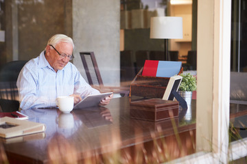 Canvas Print - Senior Man Using Digital Tablet Through Window