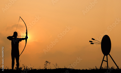 Cuadros en Lienzo Silhouette archery shoots a bow at the target.
