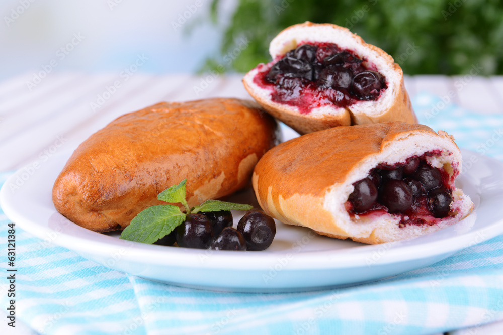 Fresh baked pasties with currant on plate on table close-up