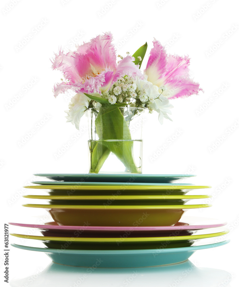 Stack of colorful ceramic dishes and flowers, isolated on white