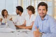 © lightwavemedia - Smiling businessman gesturing thumbs up with colleagues in meeti
