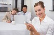 © lightwavemedia - Businesswoman text messaging with colleagues at office desk