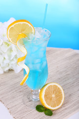 Poster - Glass of cocktail on table on light blue background