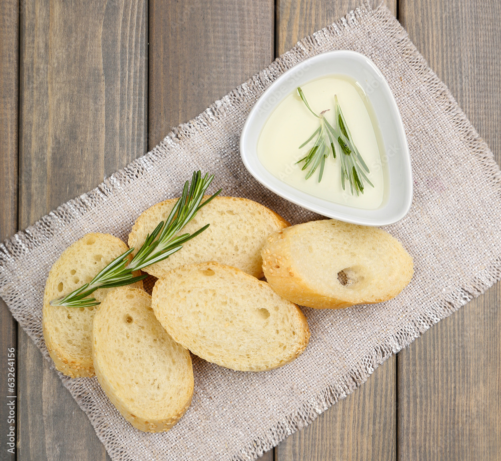 Fresh bread with olive oil and rosemary on wooden table