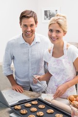 Wall Mural - Portrait of young couple preparing cookies in kitchen