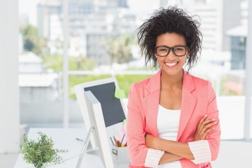 Casual female artist with arms crossed at bright office