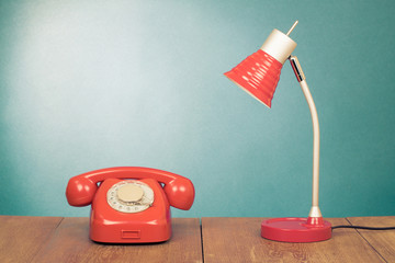 Fototapete - Retro red telephone and desk lamp on wood table