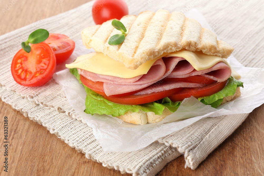 Tasty sandwich with ham on wooden table
