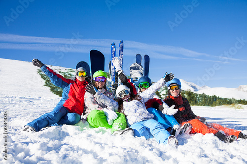 Happy friends sitting with snowboards and skis Poster