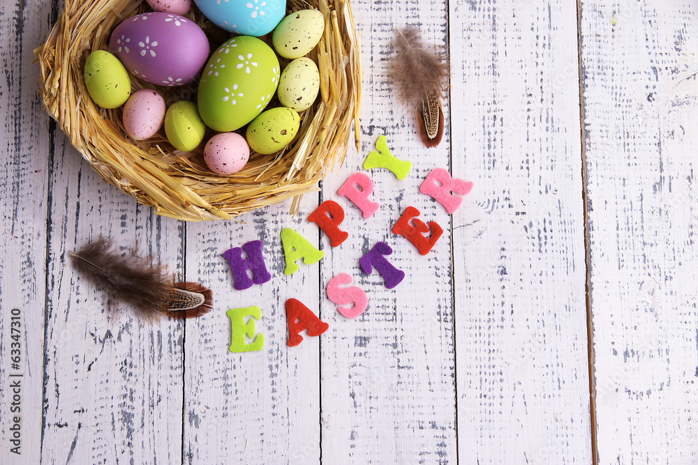 Easter eggs in nest and sign on color wooden background