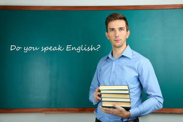 Poster - Young teacher with books near chalkboard in school classroom