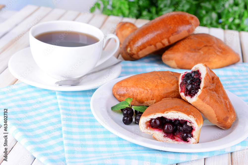 Fresh baked pasties with currant on plate on table close-up