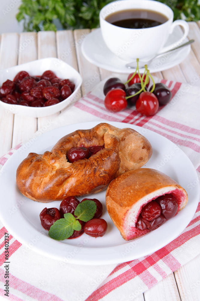 Fresh baked pasties with cherry on plate on table close-up