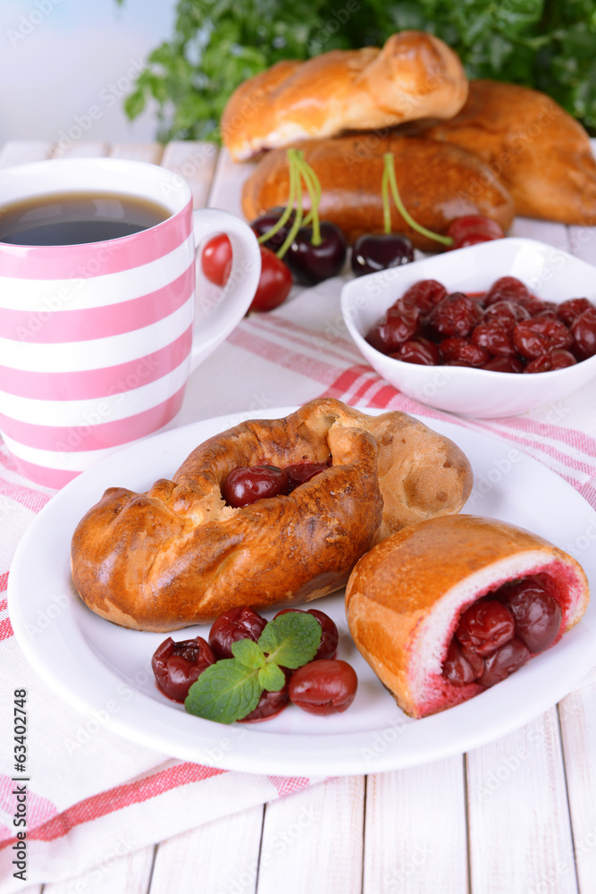 Fresh baked pasties with cherry on plate on table close-up
