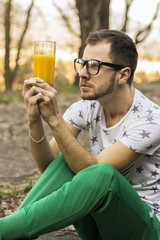 Young man looking confused at the glass with juice