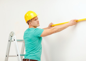 smiling man building using spirit level to measure