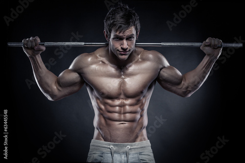 Naklejka ścienna Muscular bodybuilder guy doing exercises with dumbbells over bla