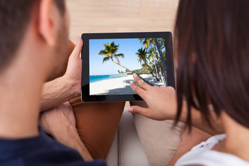 Poster - Young Couple Looking Photos On Digital Tablet Together