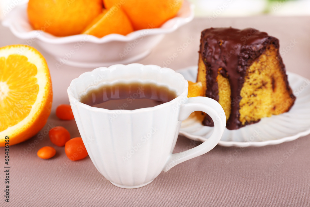 Piece of delicious cake  with oranges on tablecloth close-up