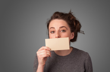 Cute girl holding white card at front of her lips with copy spac