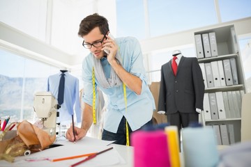 Fashion designer working on his designs while on call