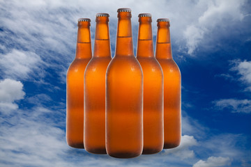 A group of five beer bottles in a diamond formation on sky backg