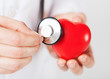male hands holding red heart and stethoscope